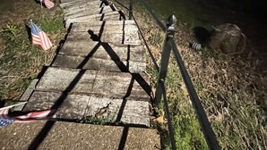 A wooden staircase leading to a dock by a lake, with American flags on the ground.