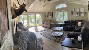 A spacious living room with a fireplace, leather sofas, and a mounted deer head.