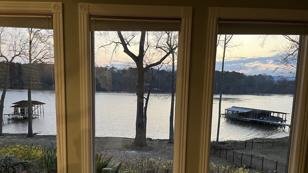 A view through three windows of a lake with docked boats and a gazebo.