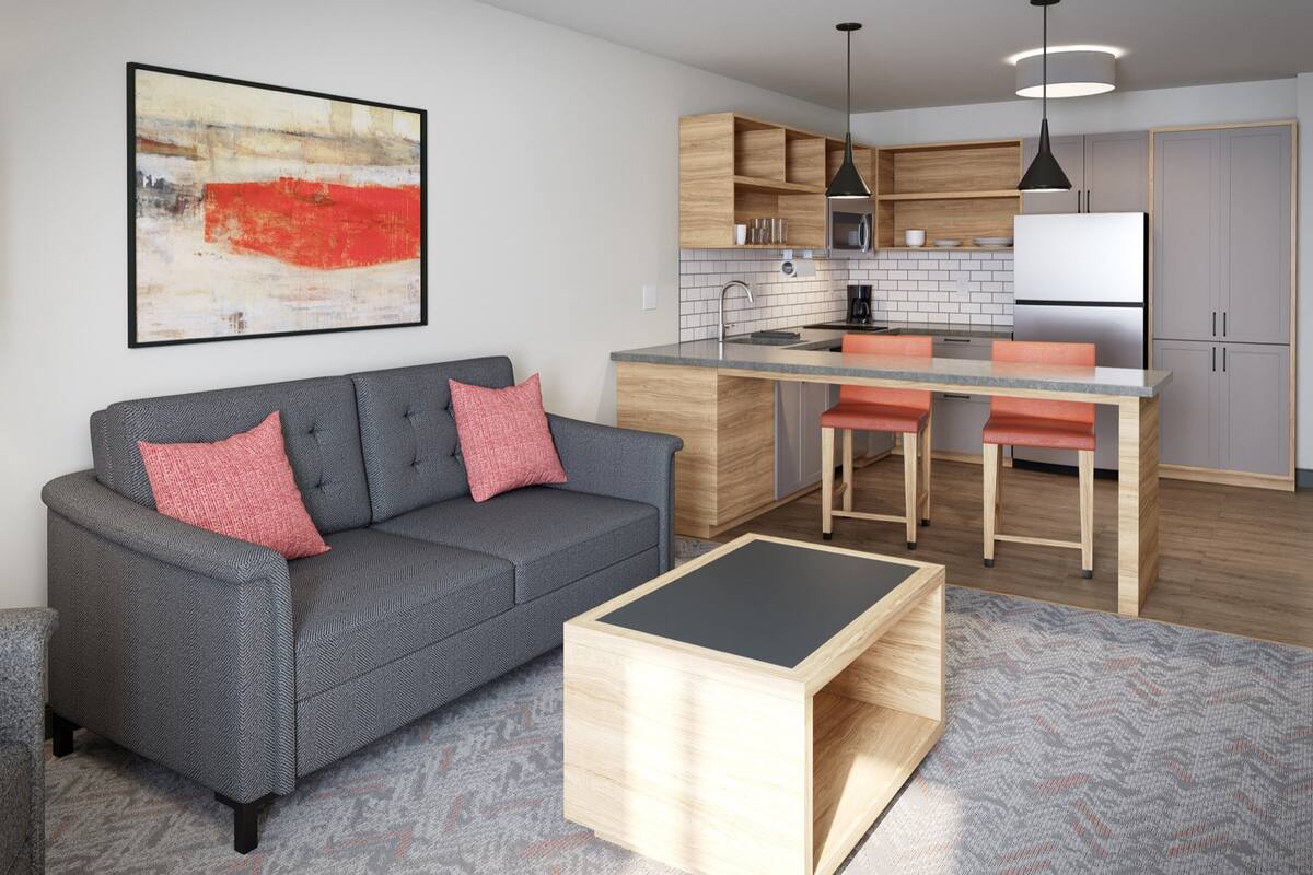 Eine moderne Küche mit Holzschränken, einer zentralen Kochinsel und einem Essbereich mit orangefarbenen Stühlen.
