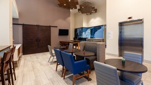 A modern dining area with wooden tables and blue chairs, a large map mural, and a digital clock on the wall.