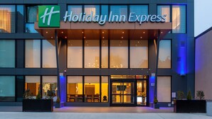 The exterior of a Holiday Inn Express hotel with a modern design, featuring large windows and a prominent entrance.