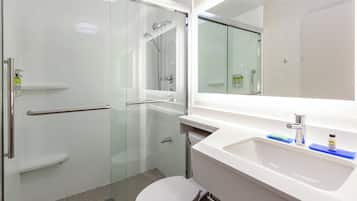 A modern bathroom with a glass-enclosed shower, a white sink, and a toilet.