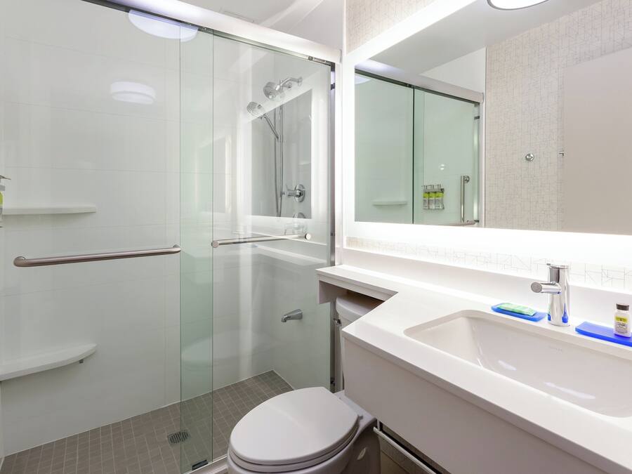 A modern bathroom with a glass-enclosed shower, a white sink, and a toilet.