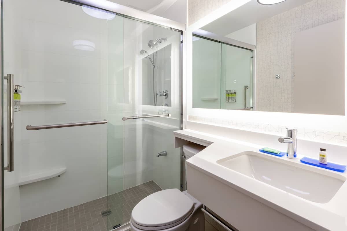Un baño moderno con cabina de ducha de vidrio, lavamanos blanco y inodoro.