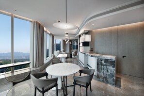 Un espace repas moderne avec une table ronde et des chaises, un comptoir de cuisine et de grandes fenêtres offrant une vue sur la ville.