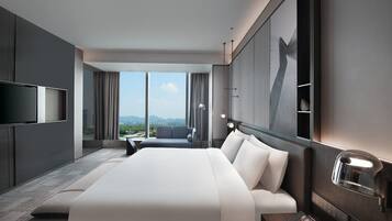 Un hotel moderno con una cama grande, televisión, escritorio y vistas a la ciudad.