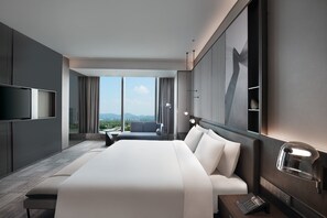Une chambre d’hôtel moderne dotée d’un grand lit, d’une télévision, d’un bureau et offrant une vue sur la ville.