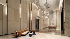 Un vestíbulo moderno con un banco, zona de estar y un techo decorativo.