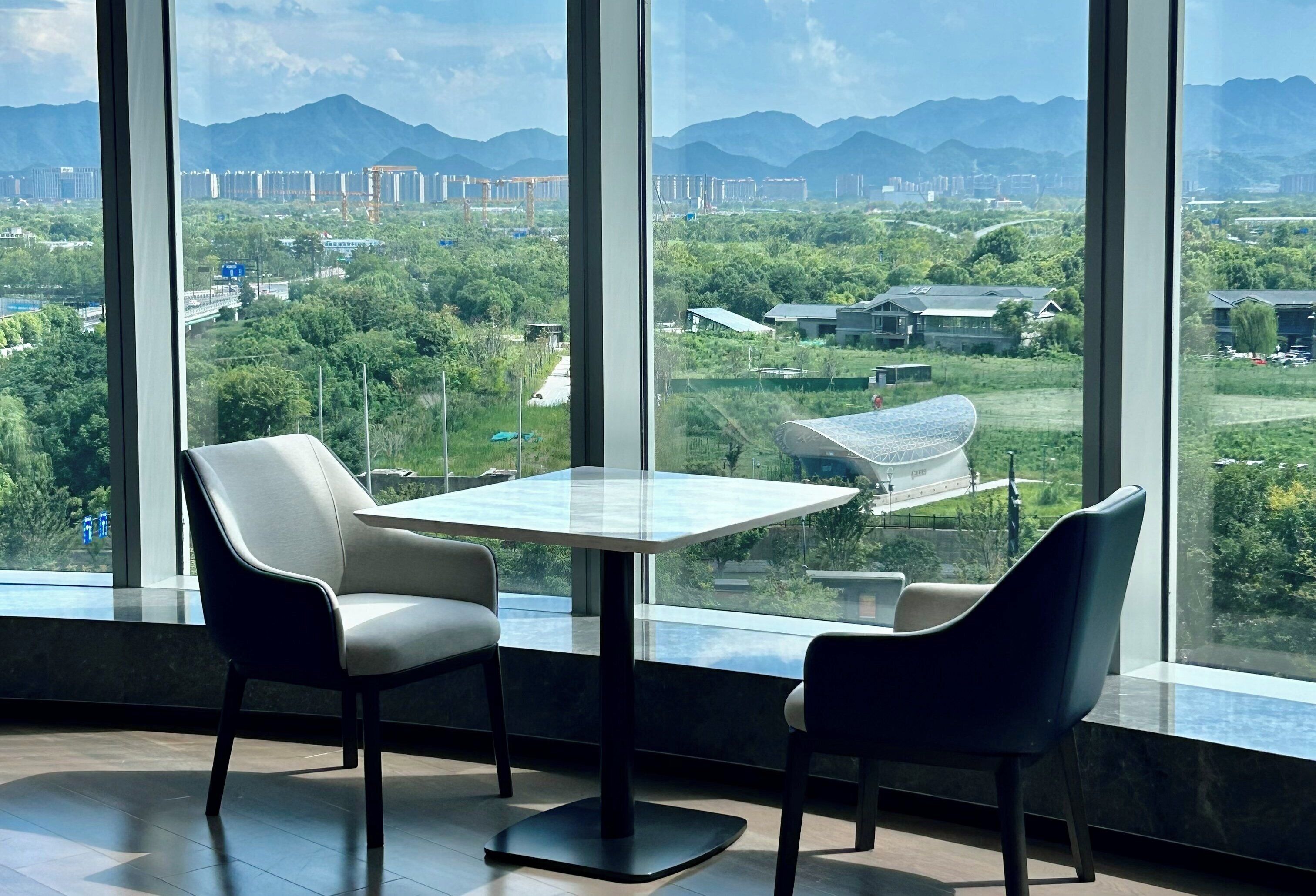 A modern room with a large window, two chairs, and a table.