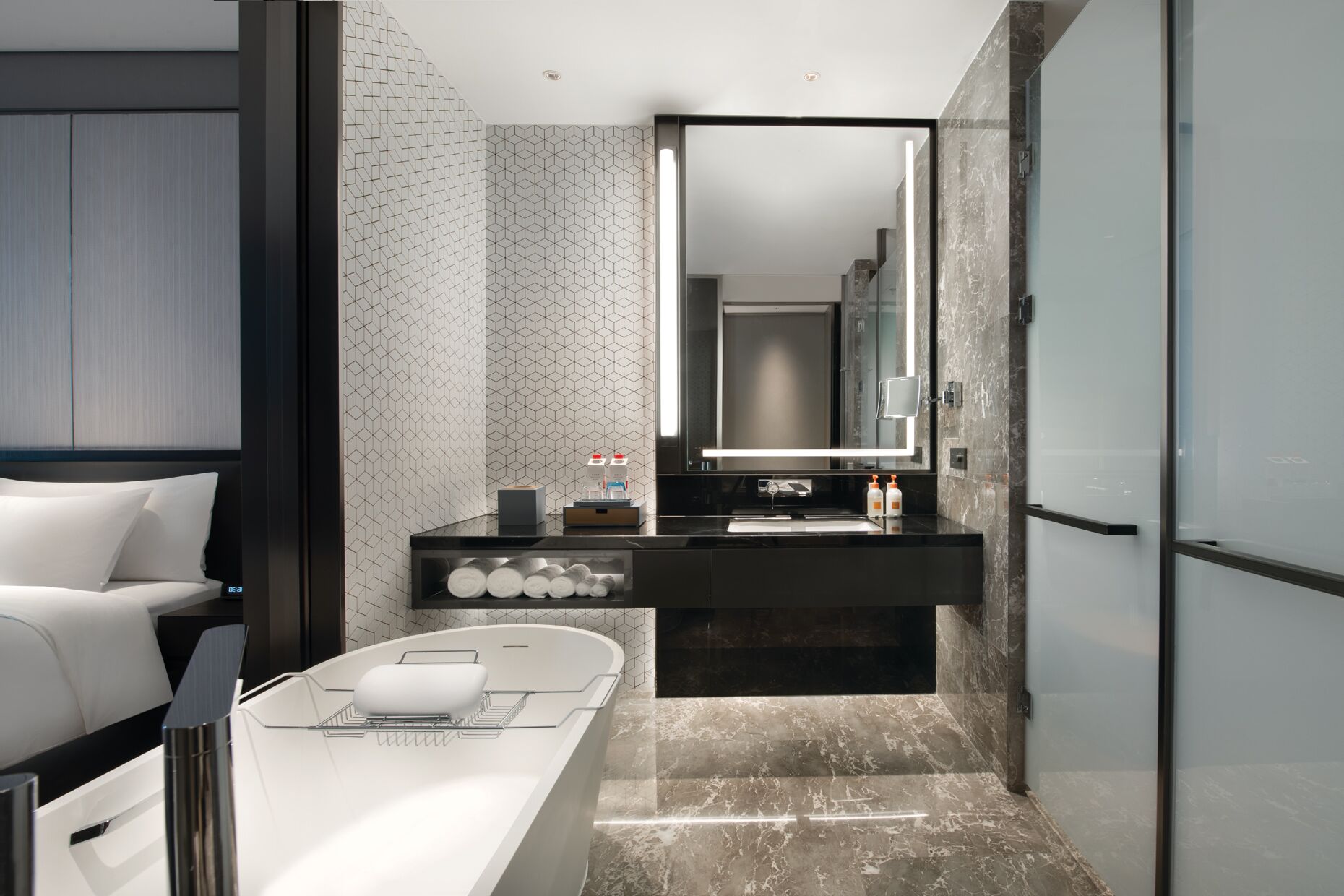 A modern bathroom with a large mirror, a bathtub, and a vanity with toiletries.