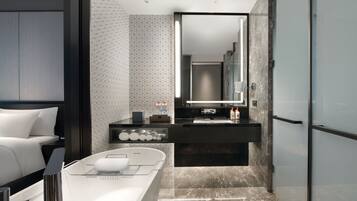 A modern bathroom with a large mirror, a bathtub, and a vanity with toiletries.