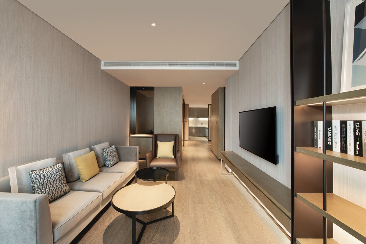 A modern living room with a sofa, coffee table, and a TV mounted on the wall.