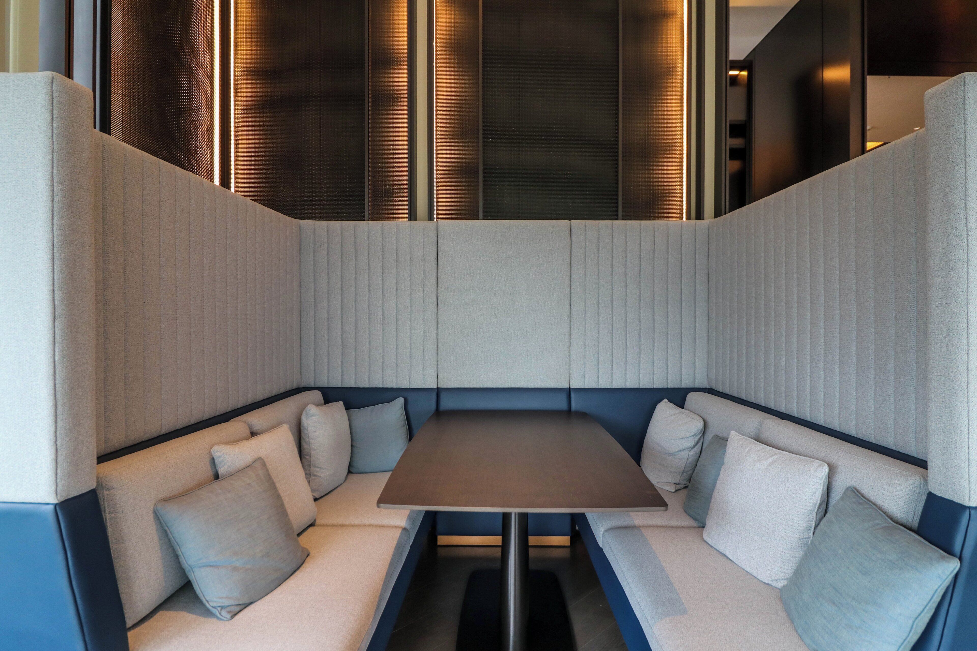 Een moderne, gezellige zithoek met een rechthoekige tafel en beklede banken.