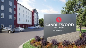 Ein Schild des Candlewood Suites, einem IHG Hotel, mit Parkplatz und Autos davor.