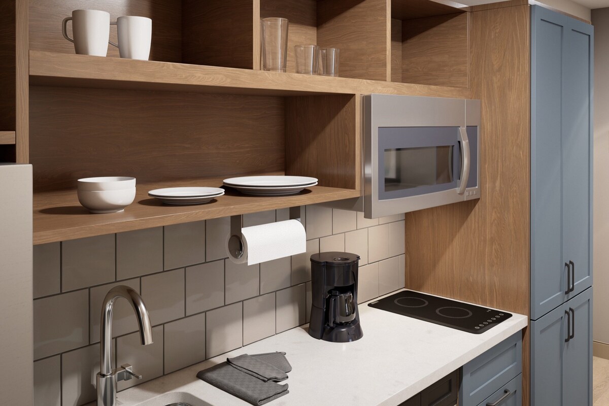 Une cuisine moderne équipée d’un four à micro-ondes encastré, d’une machine à café et d’un rouleau d’essuie-tout posé sur le plan de travail.