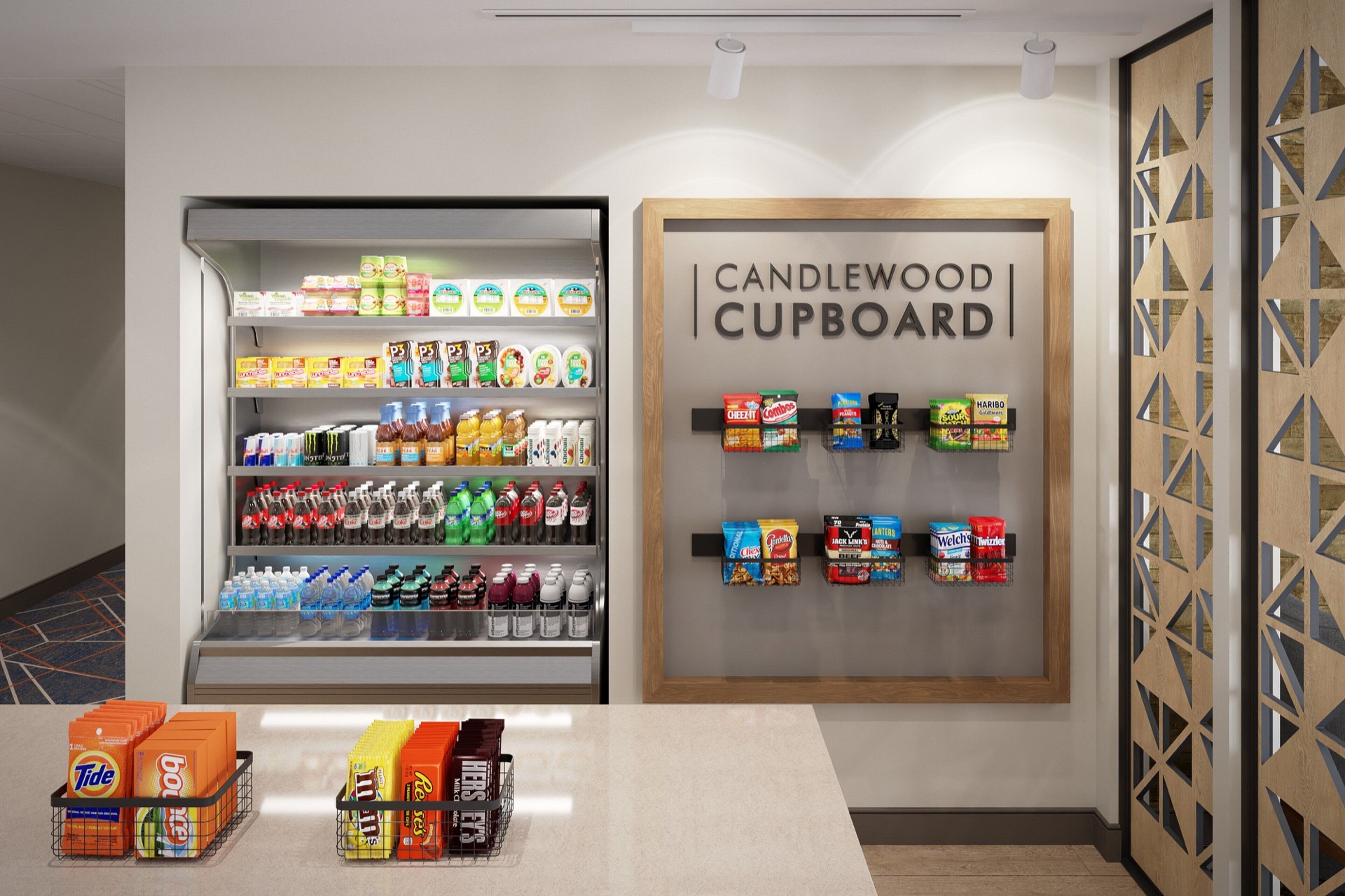 A beverage refrigerator stocked with various drinks and a display of snacks and candies.