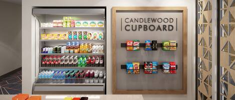 A beverage refrigerator stocked with various drinks and a display of snacks and candies.