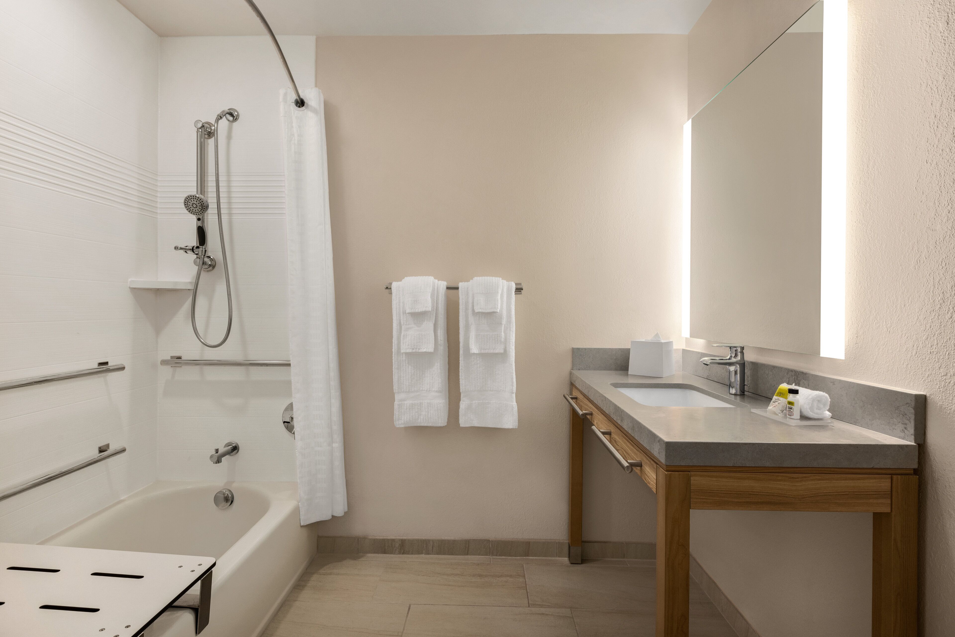 A modern bathroom with a bathtub, shower, vanity, and a large mirror.