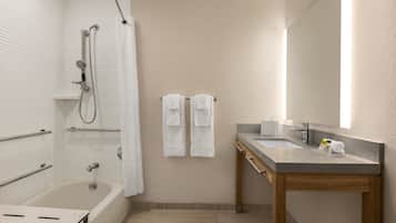 A modern bathroom with a bathtub, shower, vanity, and a large mirror.