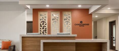 A reception desk with a wooden finish, a logo, and a wall with geometric patterns.