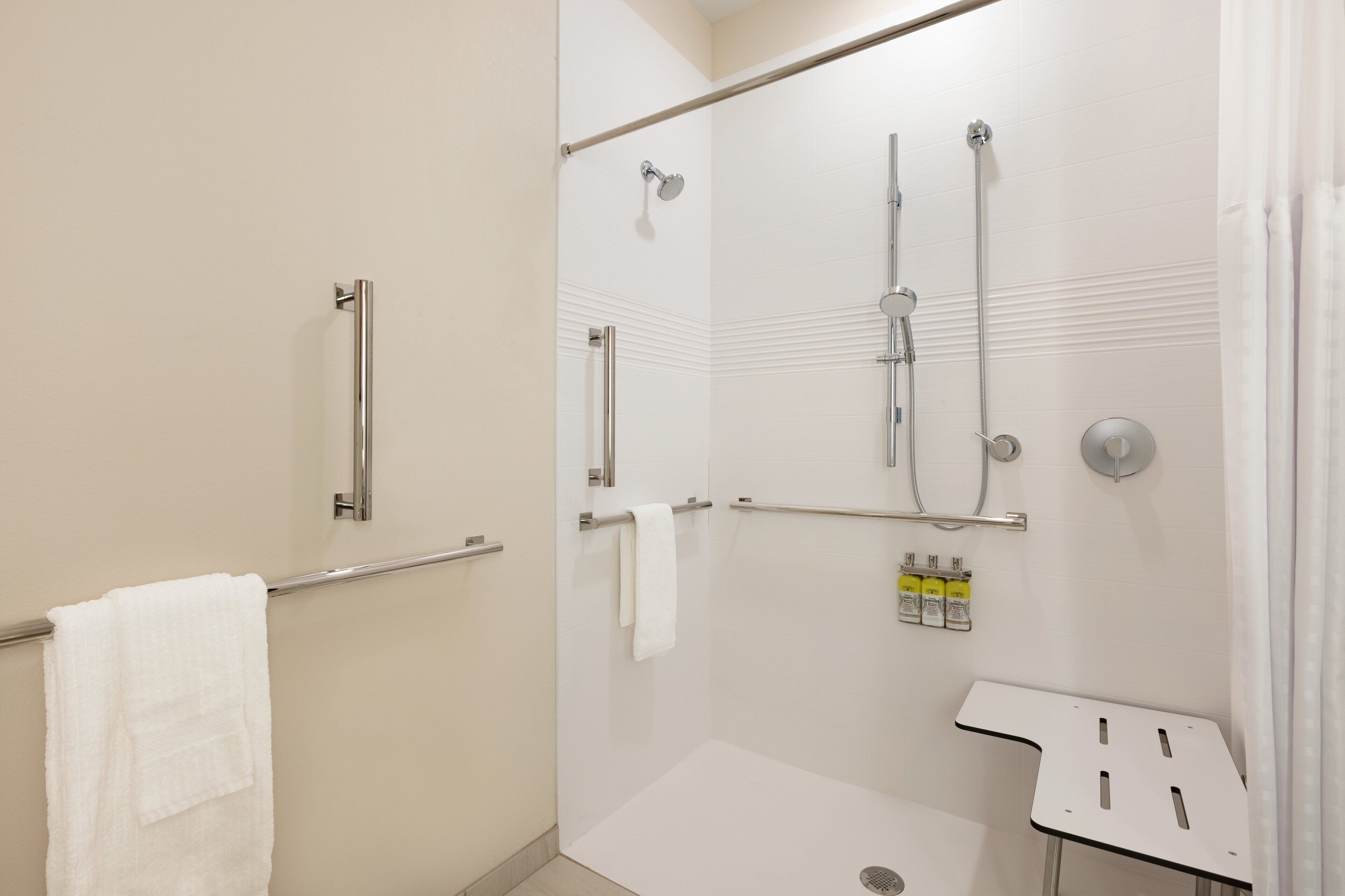 A modern shower area with a glass door, a white towel, and a small table with toiletries.