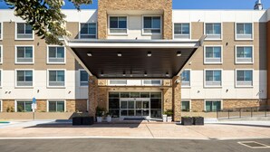 Un bâtiment moderne doté d’un porche, de nombreuses fenêtres et d’une façade en pierre.