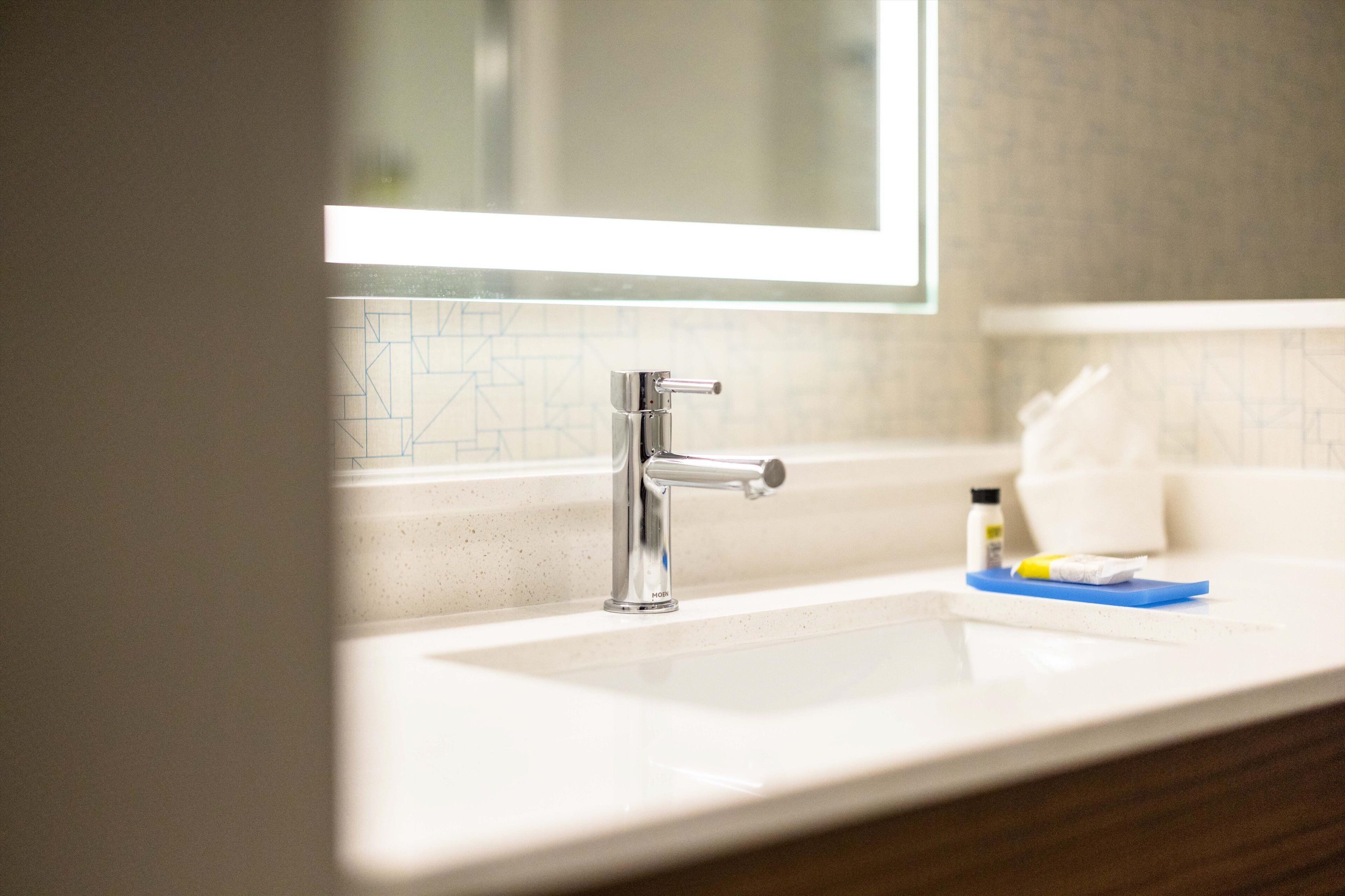 A bathroom sink with a chrome faucet, a mirror above it, and a towel on the counter.