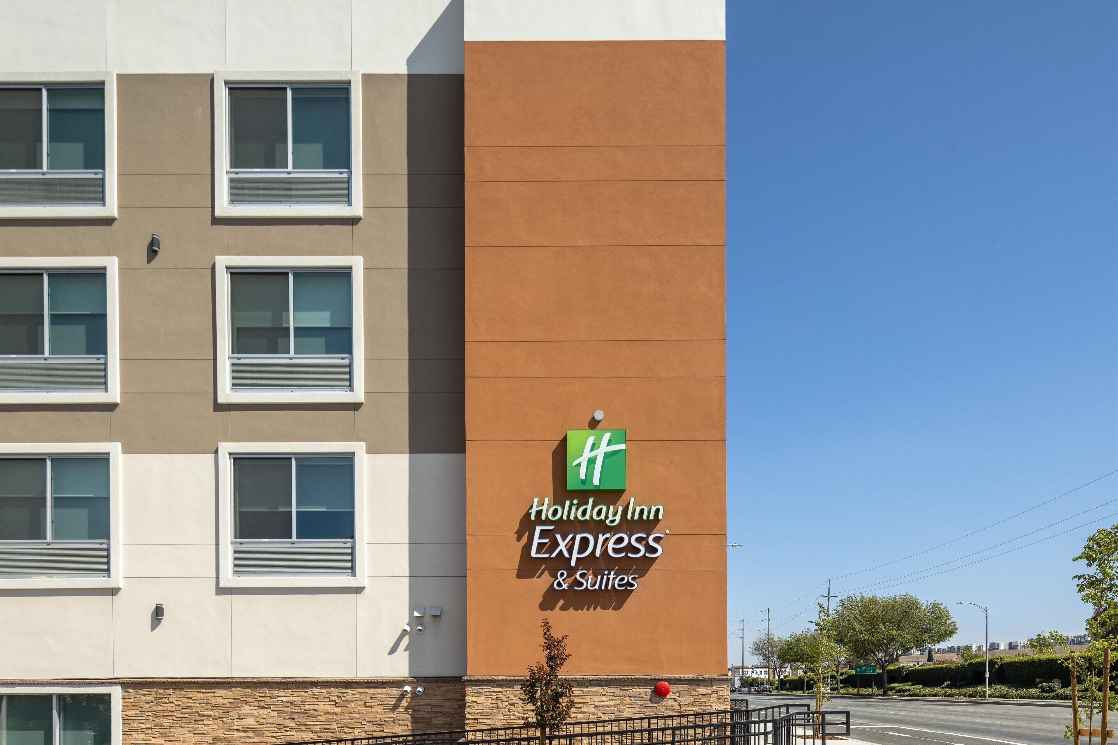 A Holiday Inn Express & Suites building with a modern facade, multiple windows, and a clear sky.