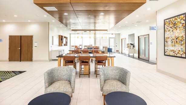 Un hall d’hôtel moderne comprenant un espace repas, des coins salon et une grande œuvre d’art accrochée au mur.