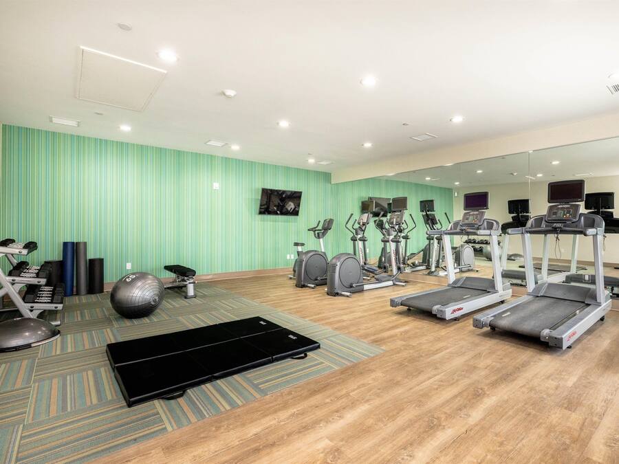 Ein Fitnessstudio mit Laufbändern, Crosstrainern und Übungsbällen.