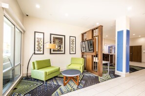 A modern hotel lobby with a green sofa, a round table, and a bookshelf. - Holiday Inn Express & Suites San Jose Silicon Valley by IHG (San Jose)