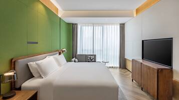Ein modernes Hotelzimmer mit einem großen Bett, einem Fernseher und einer kleinen Sitzecke.