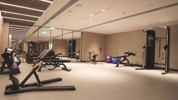 Een moderne sportschool met diverse fitnessapparaten, waaronder loopbanden, krachttoestellen en losse gewichten.