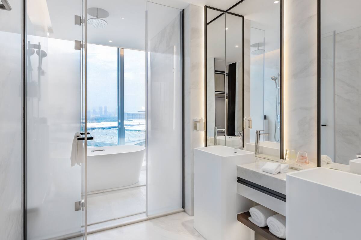 A modern bathroom with a glass-enclosed shower, two sinks, and a large mirror.