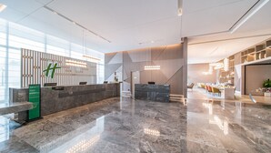 A modern hotel lobby with marble floors, a reception desk, and a dining area with chairs and tables. - Holiday Inn Xi an Chanba by IHG (Xi'an)