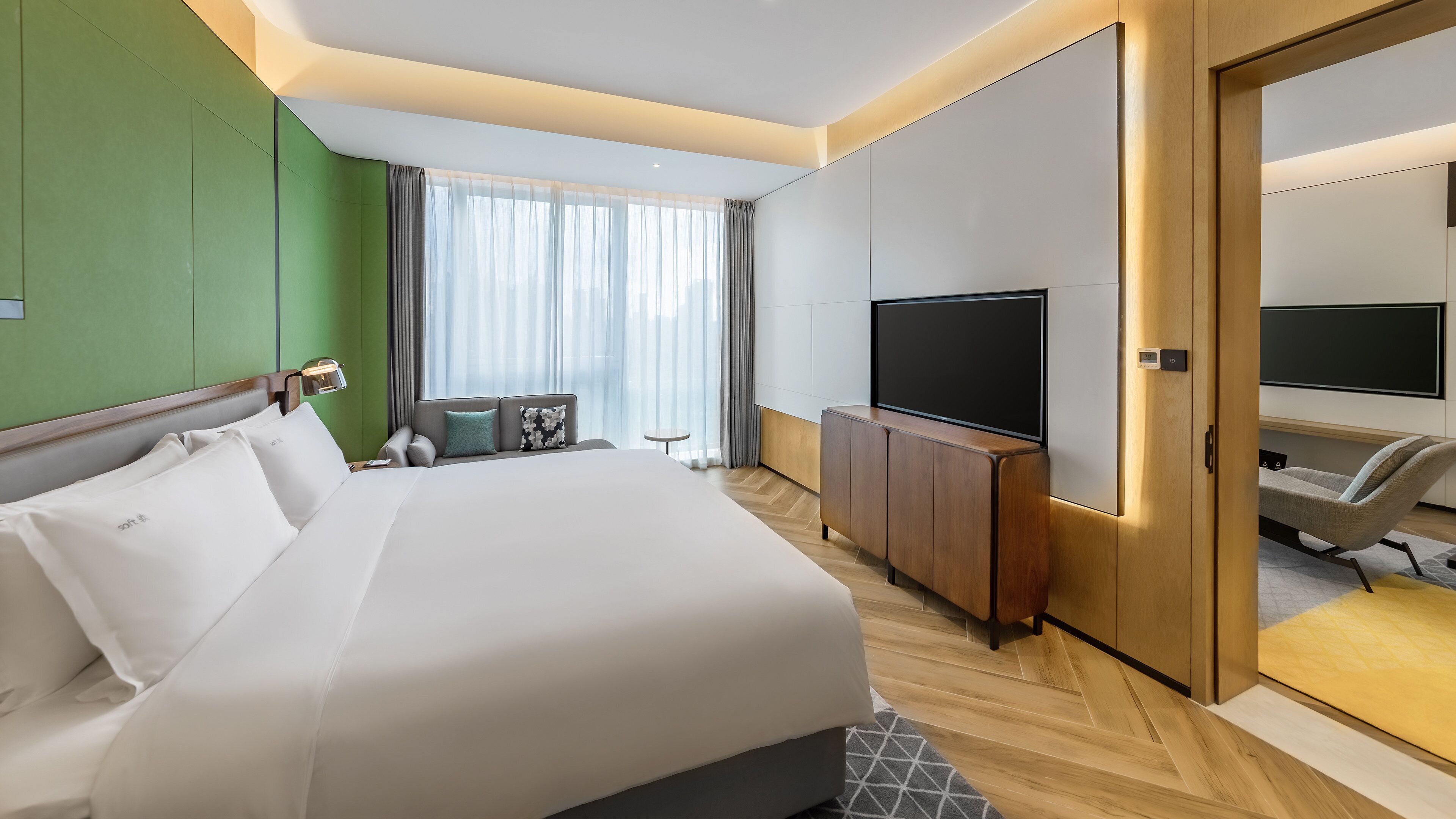 Ein Hotelzimmer mit einem großen Bett, einem Fernseher, einem Schreibtisch und einem Sessel.