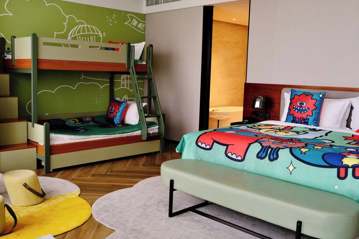 A room with bunk beds, a desk, and a bed with a colorful blanket.