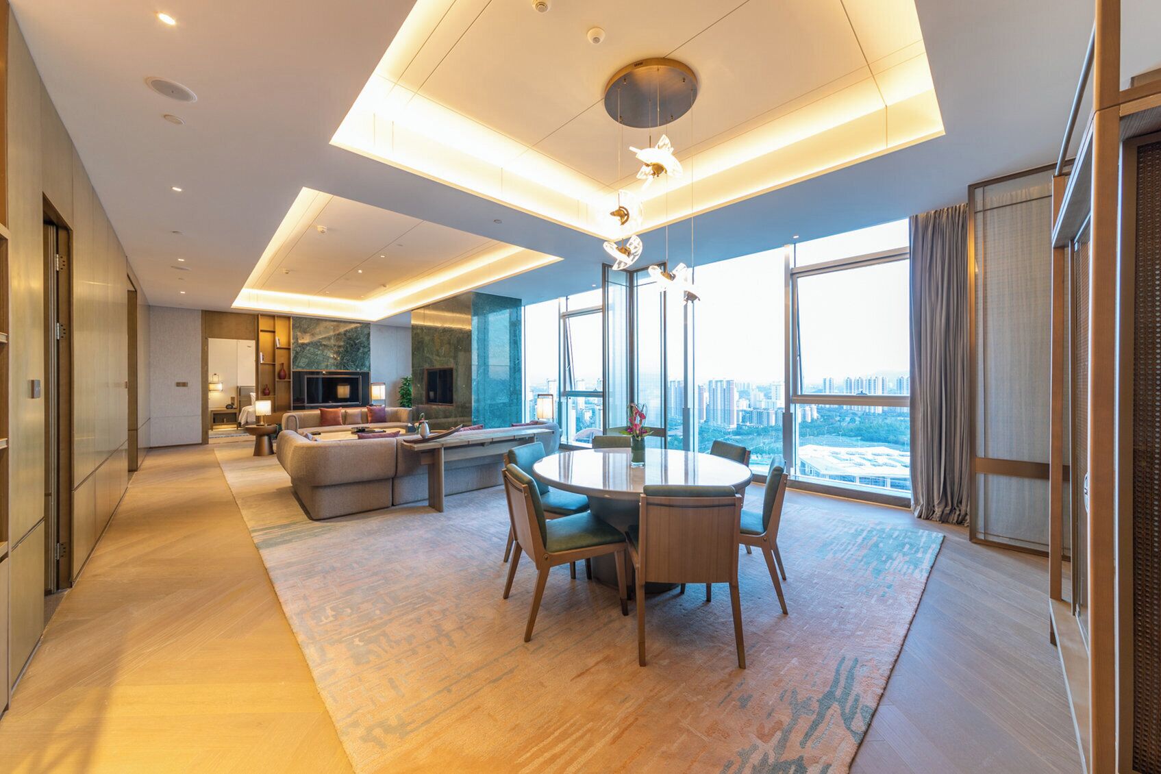 Habitación de hotel moderna con una amplia mesa de comedor, asientos cómodos, un sofá, zona de cocina y vistas a la ciudad.
