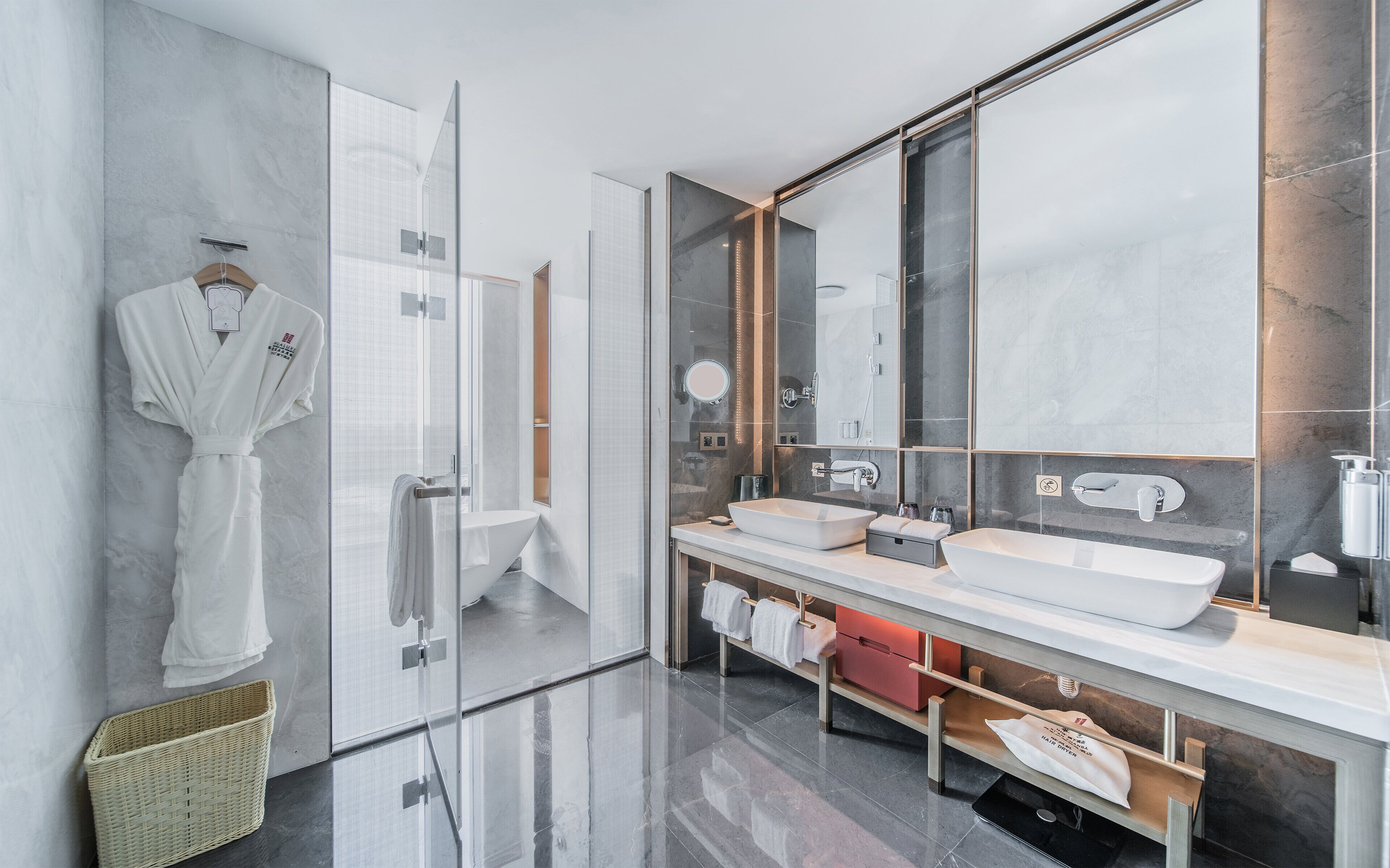 Un baño moderno con cabina de ducha de vidrio, un espejo grande y un tocador con dos lavamanos.
