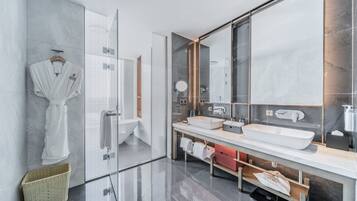 Un baño moderno con cabina de ducha de vidrio, un espejo grande y un tocador con dos lavamanos.