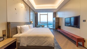 Ein modernes Hotelzimmer mit einem großen Bett, einem an der Wand montierten Fernseher und Blick auf die Stadt.