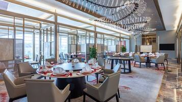 A modern dining area with round tables, chairs, and a unique ceiling light fixture.