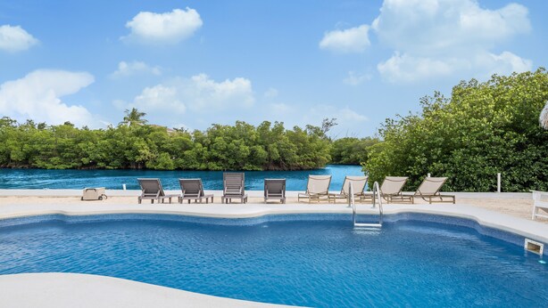 A swimming pool with lounge chairs and a view of the sea. - Waterfront Private Home-7 BR, 6 Full BA, Pool, 80' Dock, Parking, Screened Porch (Marathon)
