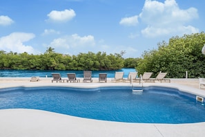 A swimming pool with lounge chairs and a view of the sea. - Waterfront Private Home-7 BR, 6 Full BA, Pool, 80' Dock, Parking, Screened Porch (Marathon)