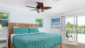 A bedroom with a large bed, a ceiling fan, and a balcony with a view of the ocean. - Waterfront Private Home-7 BR, 6 Full BA, Pool, 80' Dock, Parking, Screened Porch (Marathon)