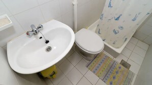 Ein kleines Badezimmer mit einem weißen Waschbecken, einer Toilette und einer Duschvorhang mit Tiermotiven.