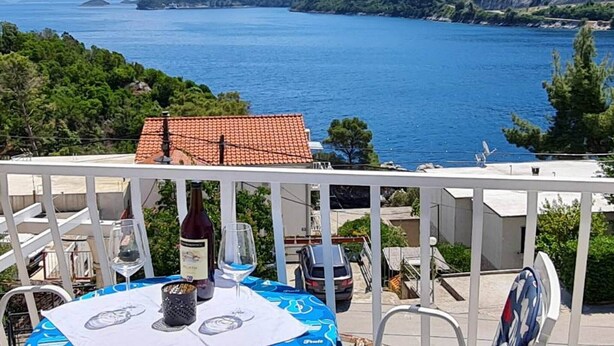 Eine Terrasse mit Essplatz, die auf eine Küstenlandschaft mit Hügeln und dem Meer blickt.