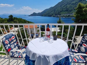 Un balcone con tavolo apparecchiato per due, con vista sul paesaggio costiero.