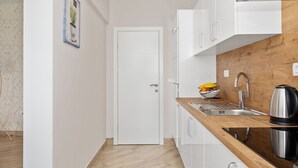 Eine moderne Küche mit weißen Schränken, einer Holz Arbeitsplatte, einer Edelstahl-Spüle und einem Wasserkocher.